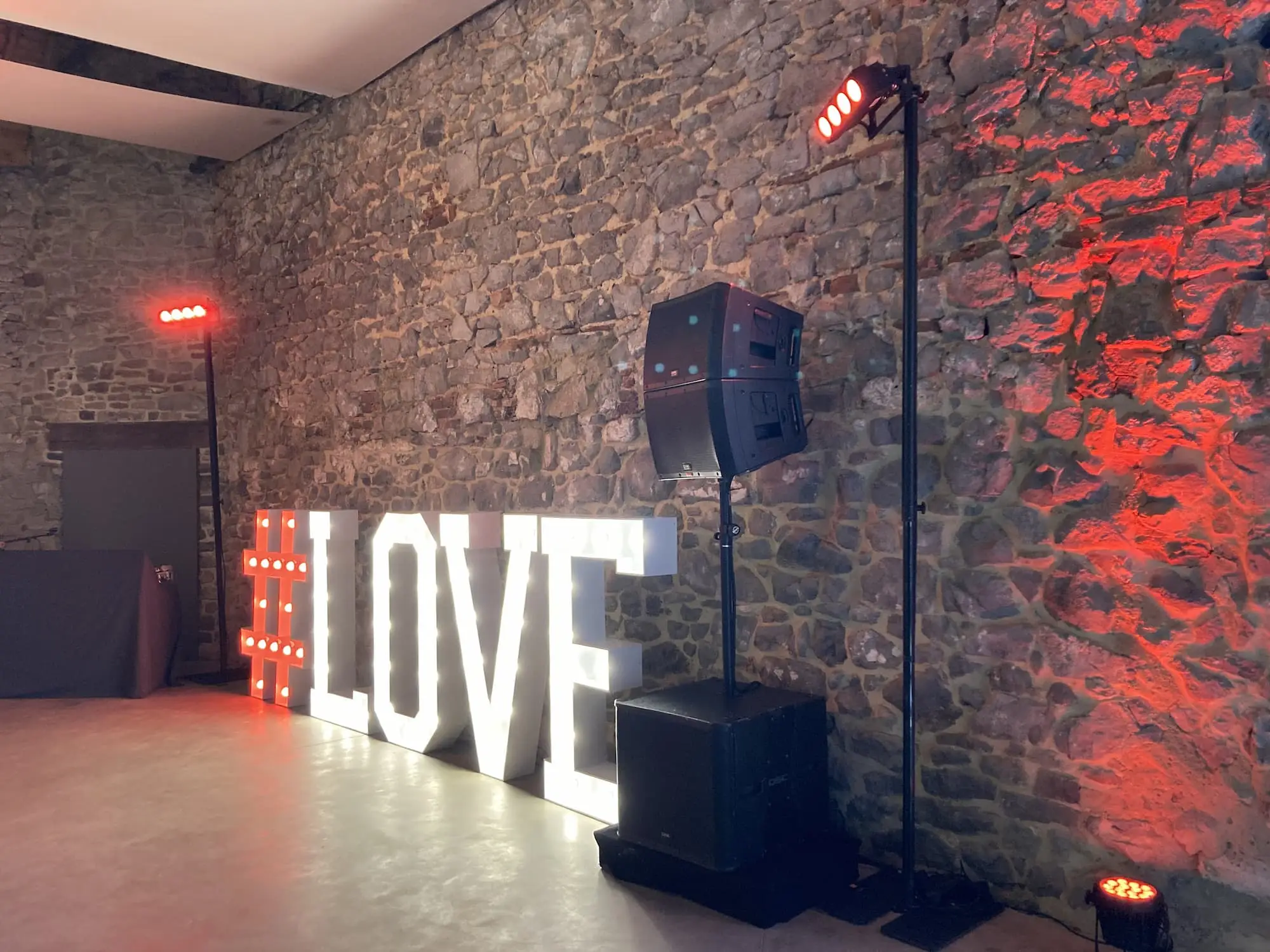 Lettres lumineuses « LOVE », enceinte et éclairage dans une salle aux murs de pierre