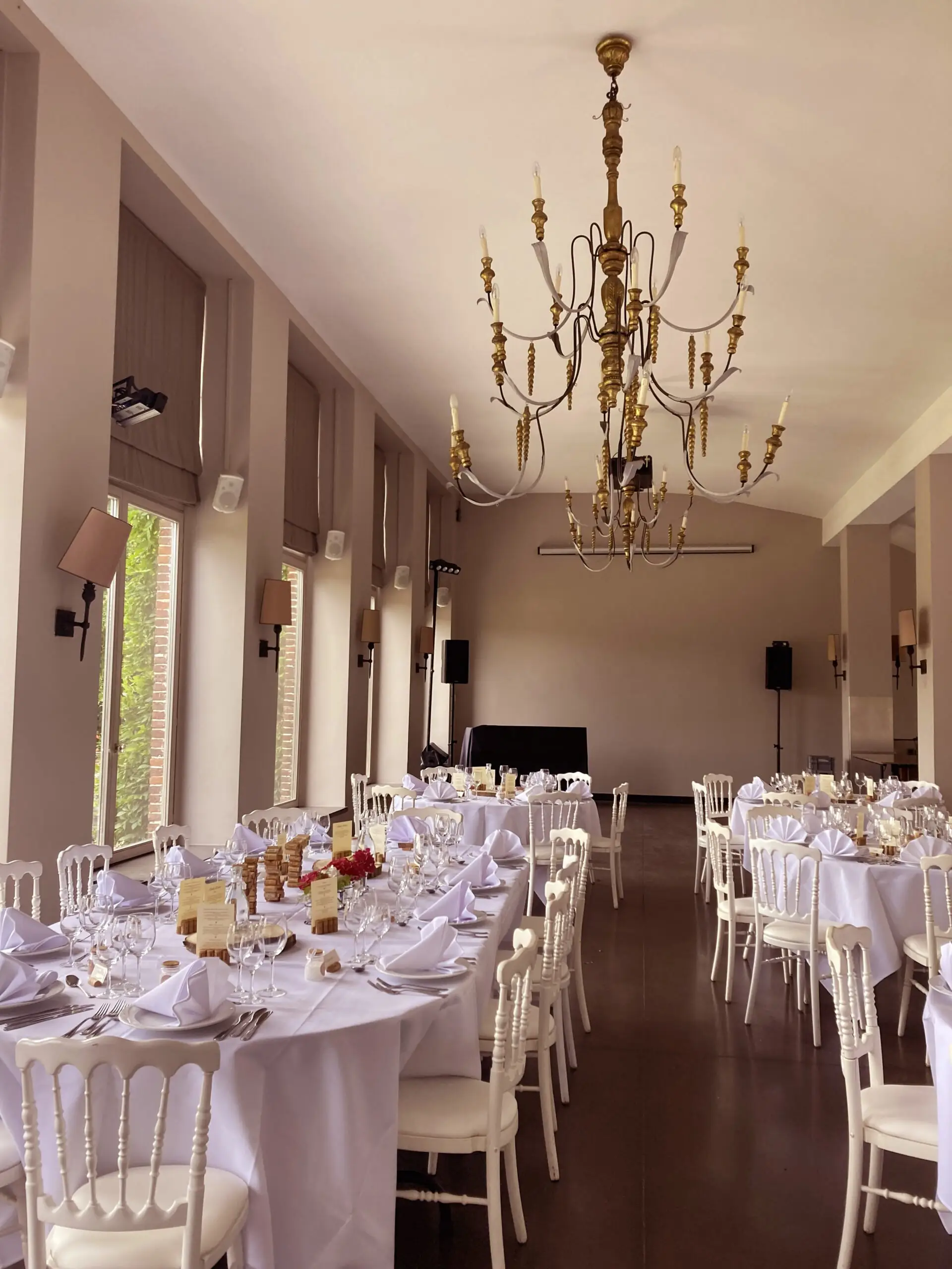 Salle de réception aux tables rondes dressées sous des lustres